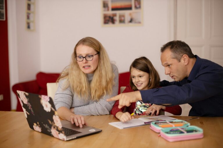 Parents sitting at a table with their daughter and a laptop, working through NDIS plan management options together