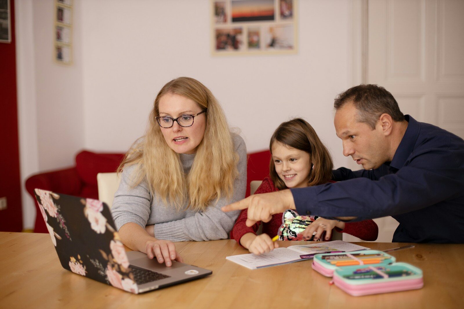 Parents sitting at a table with their daughter and a laptop, working through NDIS plan management options together